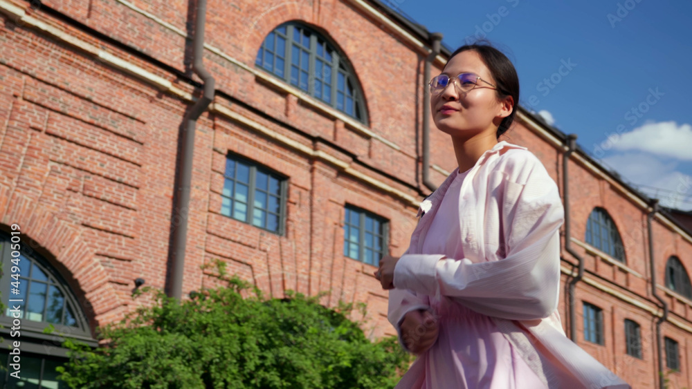 Low angle view of stylish asian woman dancing outdoors Low angle view of stylish asian woman dancing outdoors