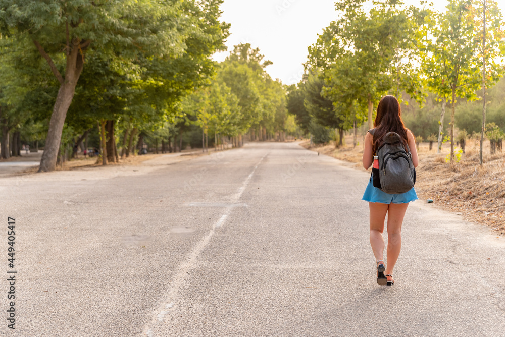 Young caucasian girl walking backwards in the park.