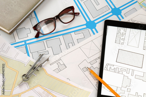 Office stationery, eyeglasses and tablet on cadastral maps of territory with buildings, flat lay