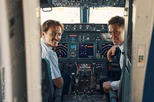 Fotografiet Joyous pilot and a co-pilot looking out of the cockpit