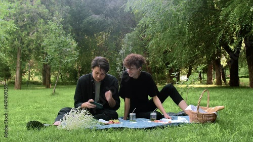 The guy plays the game on the phone, and the second watches the process in nature in the summer