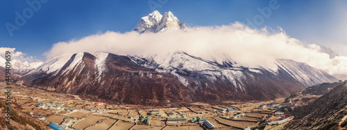 Dingboche mountain village in Imja Khola river valley and view of Ama Dablam mount at sunset in clouds. Sagarmatha National Park, Nepal. Amazing panoramic view photo