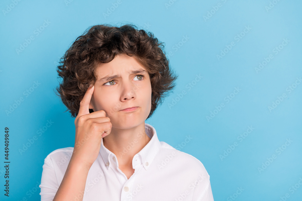 Photo of cute thoughtful schoolboy wear white shirt finger temple looking empty space isolated blue color background Photo of cute thoughtful schoolboy wear white shirt finger temple looking empty space isolated blue color background