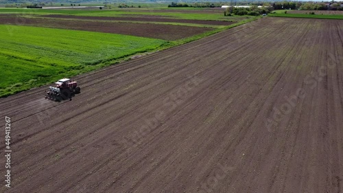 Drone flies over the tractor working on arable land