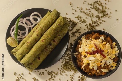 Indian flatbread made with whole wheat flour kneaded with pureed spinach and spices. Served with Green moong beans gravy with scrambled egg on top. photo