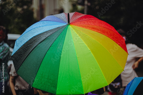 People hold rainbow umbrellas during a LGBTQ gay pride protest.