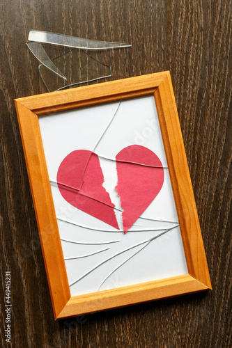Shards of glass on the table next to the photo frame. Two halves of red paper heart