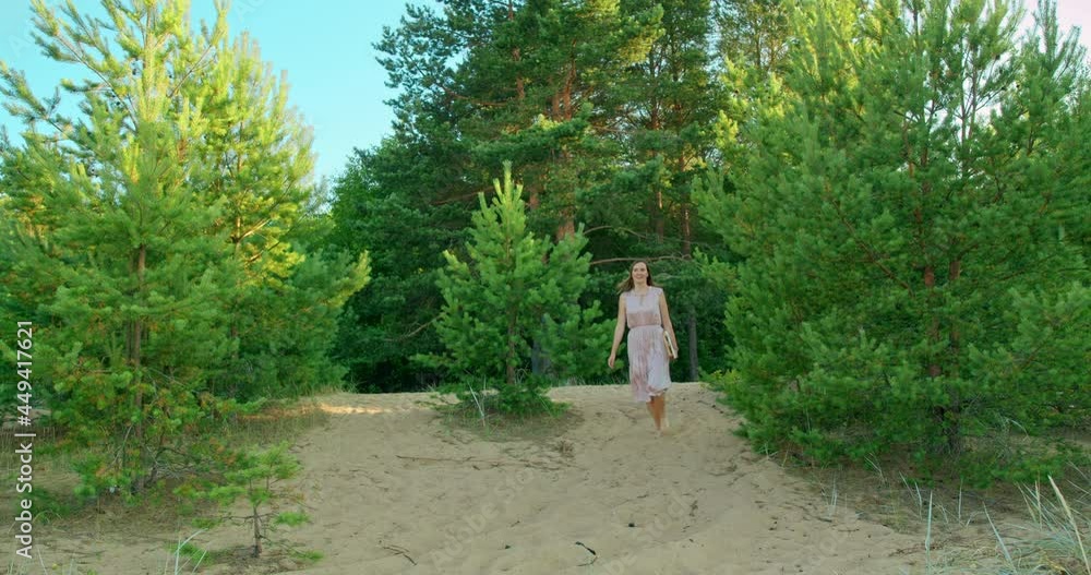 An enthusiastic young woman in a pink dress runs on the sand against the background of nature. An enthusiastic young woman in a pink dress runs on the sand against the background of nature.