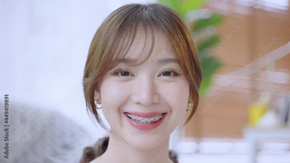 Asian woman with braces smiling until she sees wearing braces, beauty concept
Asian woman with braces smiling until she sees wearing braces, beauty concept