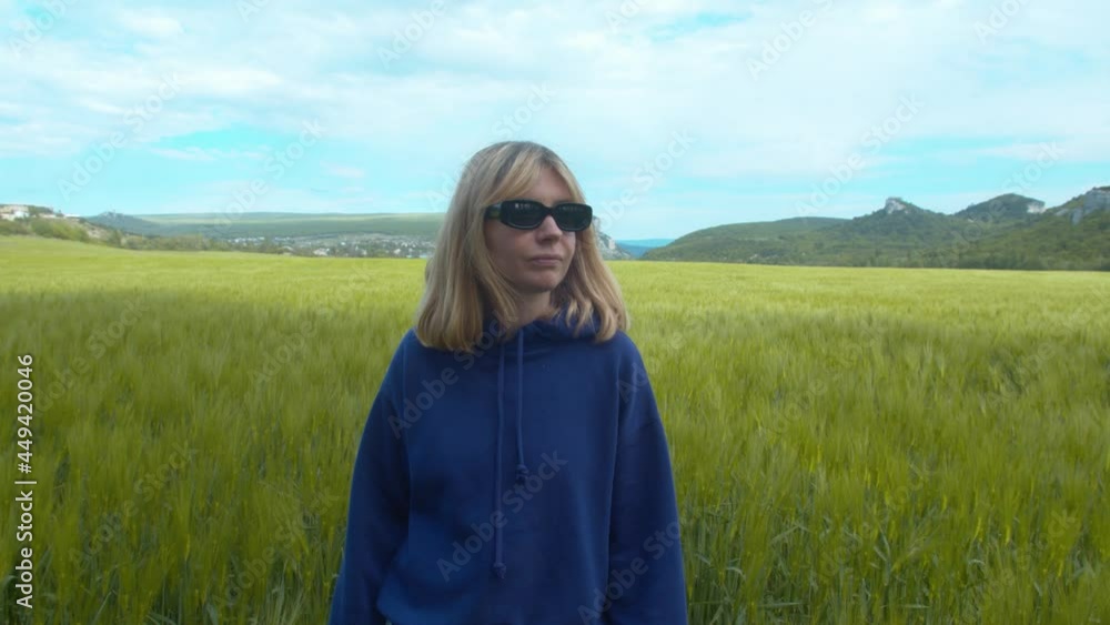 Attractive girl posing on camera outdoors. Portrait of a young woman with long hair in denim jacket looking on camera on green field background. Attractive girl posing on camera outdoors. Portrait of a young woman with long hair in denim jacket looking on camera on green field background.