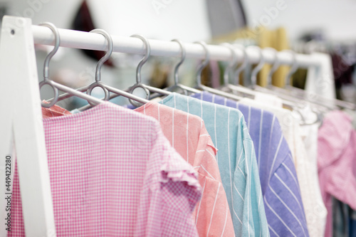Colorful women's dresses on hangers in a retail shop. Fashion and shopping concept. Variety of different female colorful clothing hanging.