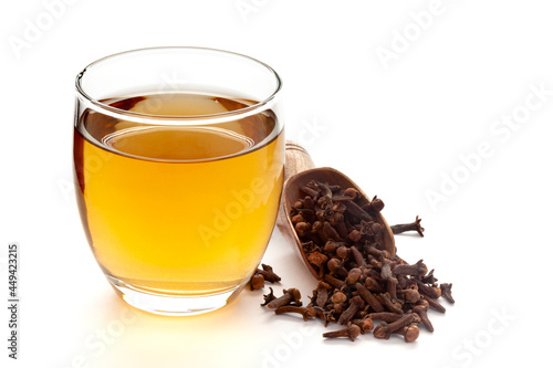 Close-Up of organic boiled water (Tea or kada ) of  clove (syzygium aromaticum ) in a transparent glass cup over white background. Original residue in bottom of tea cup photo