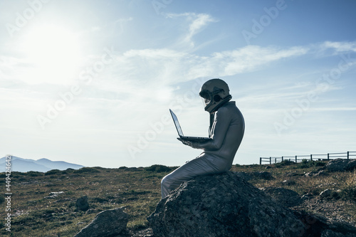 Cosmonaut using laptop near base photo