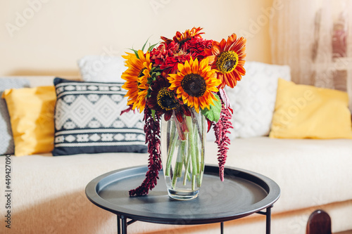 Fresh sunflowers and zinnia flowers put in vase in living room. Interior and home decor. Bouquet of fall blooms on table