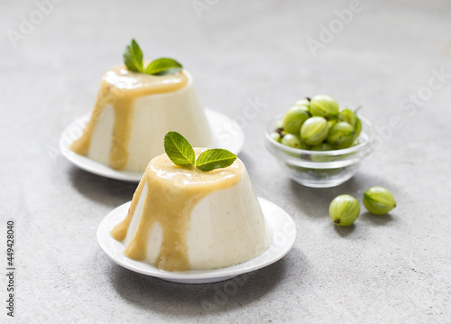 Vegan dessert, creamy gooseberry pudding with sauce on a platte on a light gray background