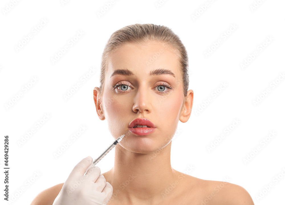 Young woman receiving filler injection in lips against white background Young woman receiving filler injection in lips against white background