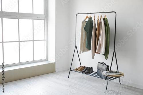 Rack with stylish clothes in room