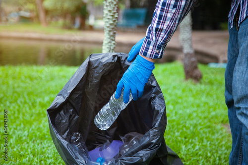 Volunteers wearing blue gloves pick up trash There are plastic water bottles, coffee mugs and other trash that people throw in the park. Ecology, environment and recycling concepts.