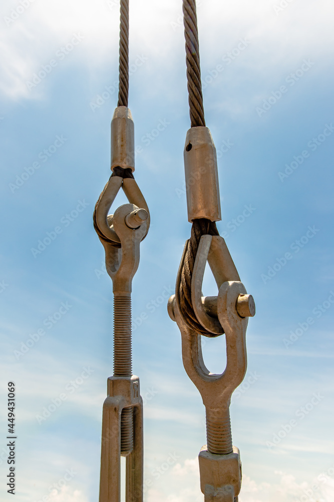 Steel turnbuckle and sling steel or Steel Wire Rope Sling and metal cable clamp connected with screw bolt. Device for adjusting the tension or length of cable on a blue sky background. Connections con