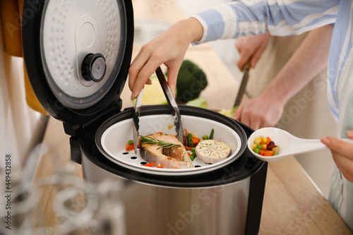 Fototapeta Naklejka Na Ścianę i Meble -  Woman cooking tasty fish in multi cooker, closeup