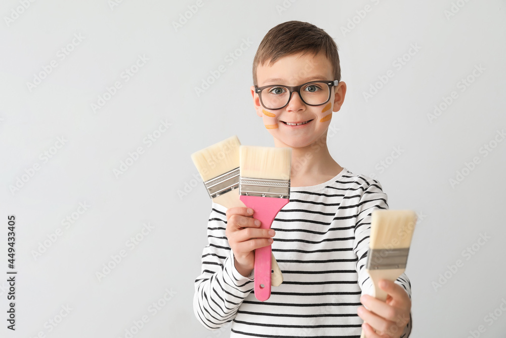 Cute little boy with brushes near light wall Cute little boy with brushes near light wall