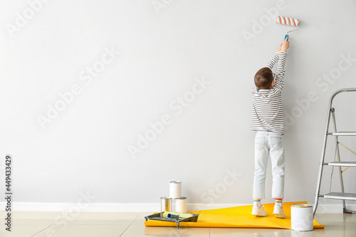 Cute little boy painting wa...