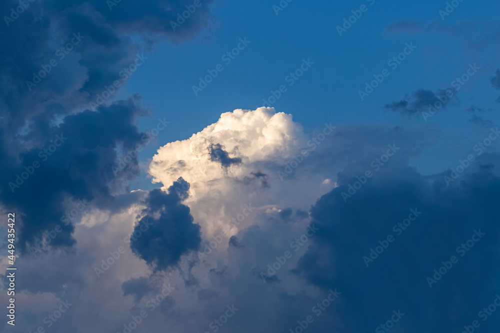 White and pink curly cloud surrounded by dark storm clouds White and pink curly cloud surrounded by dark storm clouds