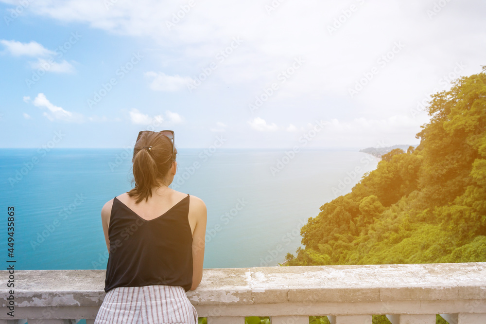 Young caucasian woman in black top overlooking the Sea and Forest. Copy space. Top View from Botanical Garden in Batumi, Adjara Georgia. Summer day. Vacation concept.