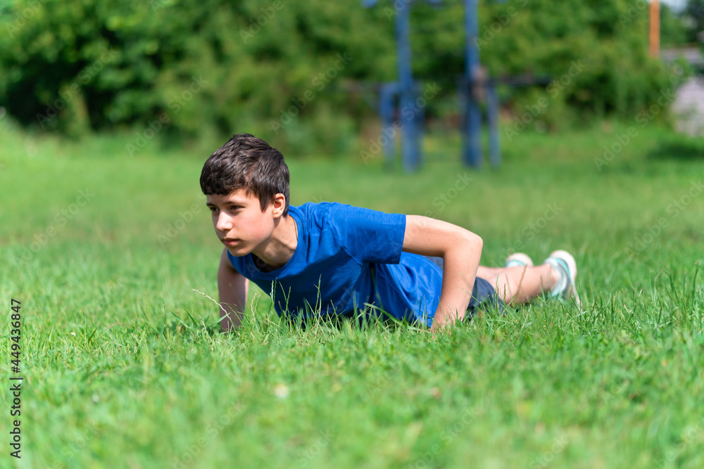 teenage boy exercising outdoors, sports ground in the yard, he does push-ups on the green grass field, healthy lifestyle teenage boy exercising outdoors, sports ground in the yard, he does push-ups on the green grass field, healthy lifestyle