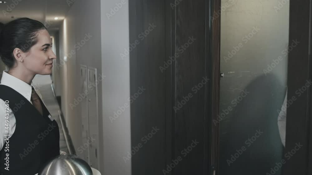 Medium shot of attractive brunette waitress knocking on door of hotel room, delivering dinner to businessman staying there on business trip Medium shot of attractive brunette waitress knocking on door of hotel room, delivering dinner to businessman staying there on business trip