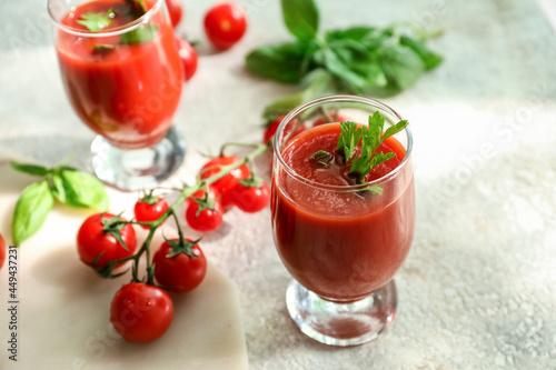 Glass of tasty tomato juice on light background