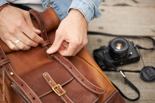 Cropped Handsome photographer male hands taking camera from leather handmade backpack, going to take photos. Photography, handmade accessories concept. copy space