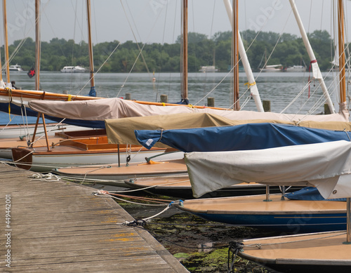 Wroxham, Norfolk Broads, UK – July 2021. Sailing boats moored along the wooden staging on the side of Wroxham Broad during the annual sailing regatta open week.