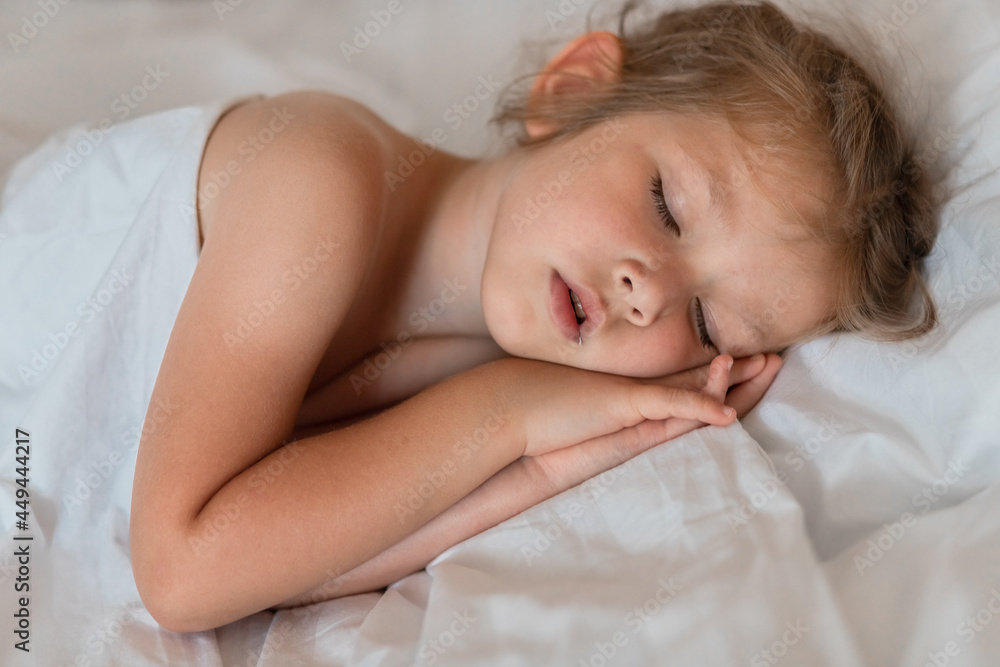 Adorable little girl sleeping in bed with white linens. Place for your text. Healthy baby sleep. Adorable little girl sleeping in bed with white linens. Place for your text. Healthy baby sleep.