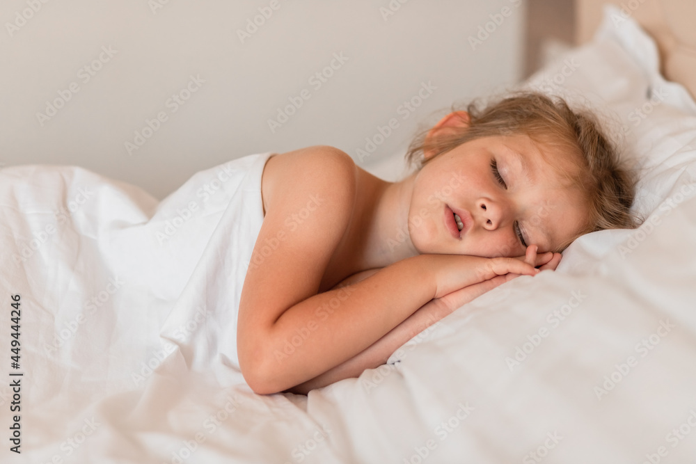 Adorable little girl sleeping in bed with white linens. Place for your text. Healthy baby sleep. Adorable little girl sleeping in bed with white linens. Place for your text. Healthy baby sleep.
