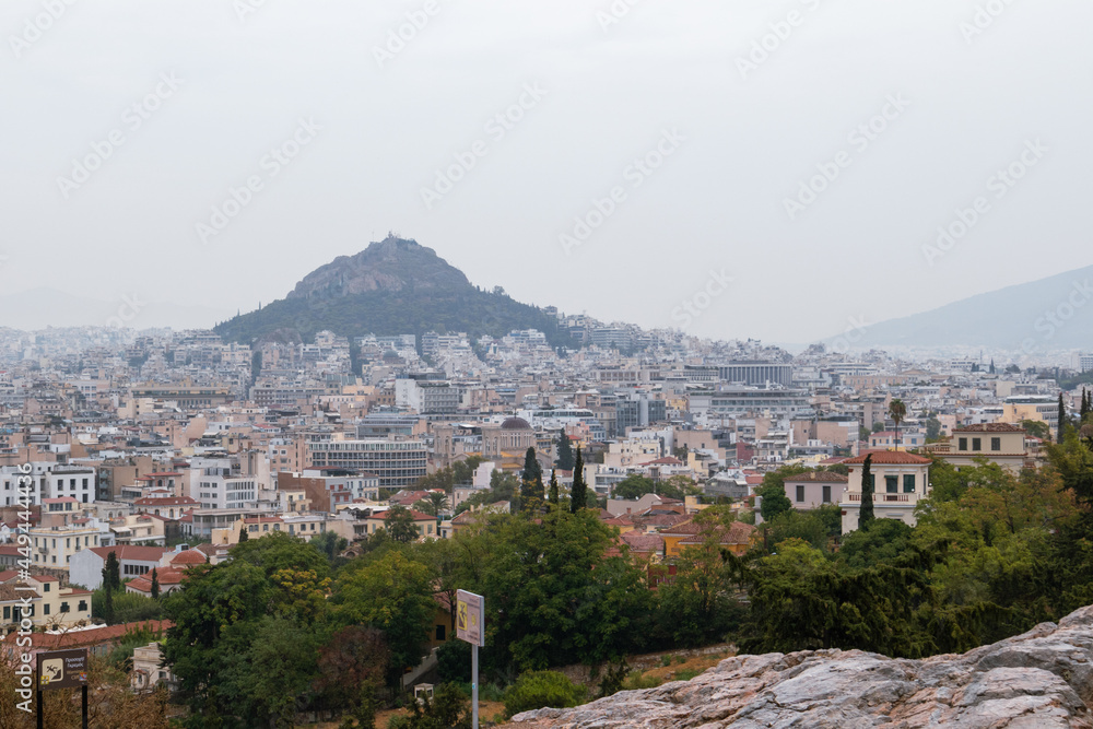 View on mount Lycabettus and Athens old city center with summer greenery in gray foggy day from Areopagus - Hill near Acropolis