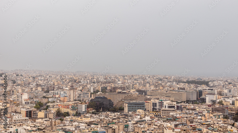 Modern Athens city center overcrowded streets with white buildings architecture on cloudy foggy day. Rooftop view from Filopappou Hill near Acropolis, Greece