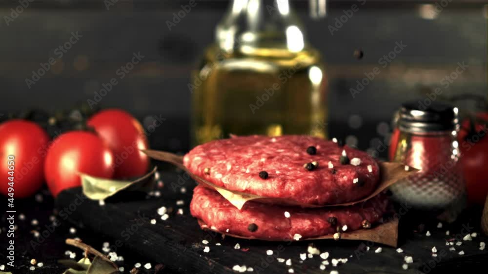 Super slow motion spices fall on the raw burger. On a black background. Filmed on a high-speed camera at 1000 fps. Super slow motion spices fall on the raw burger. On a black background. Filmed on a high-speed camera at 1000 fps.
