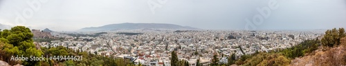 Wide panorama on Athens city center with white architecture buildings, Acropolis and mountains in vivid greenery on cloudy dramatic day from Filopappou Hill © Kathrine Andi