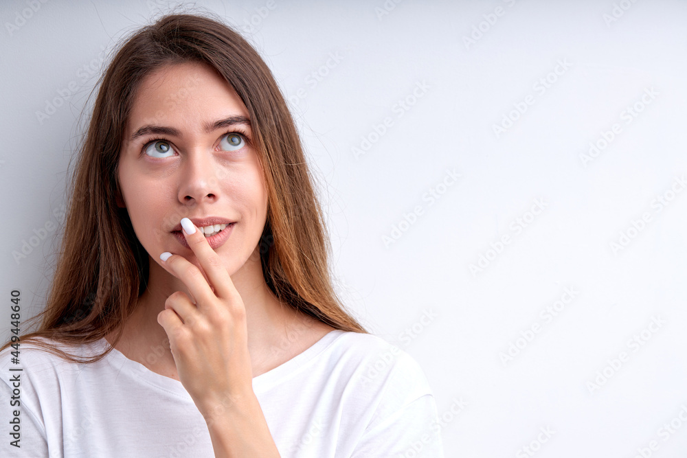 Thoughtful caucasian woman posing at camera isolated on white studio background, portrait of attractive female with long hair looking up touching mouth, in contemplation, casually dressed. copy space Thoughtful caucasian woman posing at camera isolated on white studio background, portrait of attractive female with long hair looking up touching mouth, in contemplation, casually dressed. copy space