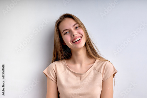 Portrait of attractive caucasian teenage girl isolated on white background, smiling happily, in casual wear, enjoying life, in good mood, posing at camera, having natural long hair and big lips.