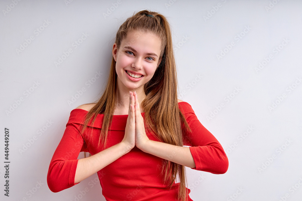 Portrait of positive teen girl keeping hands together looking at camera amiling, looking happy, dreaming thinking, isolated on white studio background, female asking something. copy space Portrait of positive teen girl keeping hands together looking at camera amiling, looking happy, dreaming thinking, isolated on white studio background, female asking something. copy space