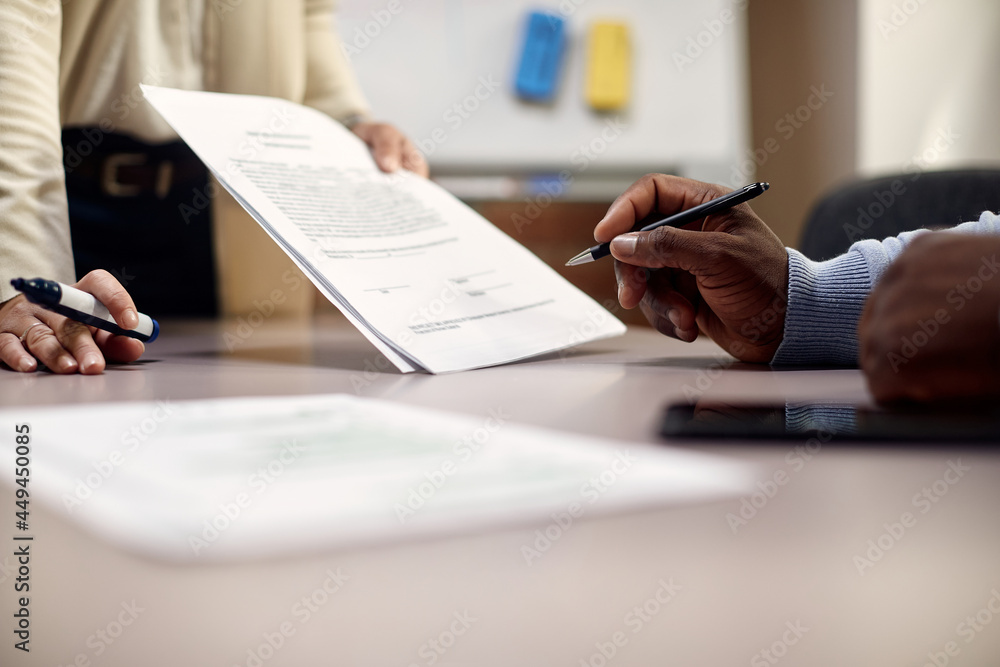 Fototapeta premium Close-up of African American CEO signs document in office.