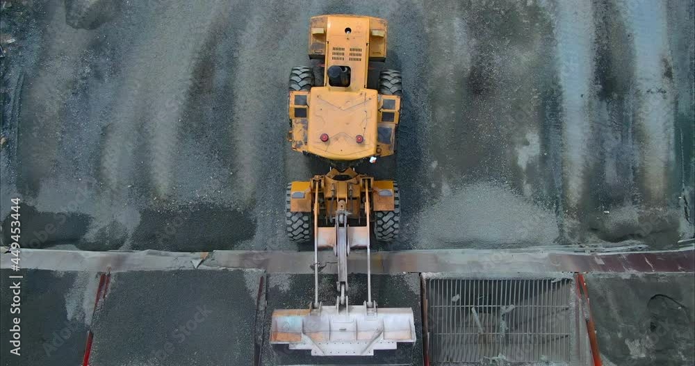 Loader unloads the asphalt from the bucket into a hopper or container ...