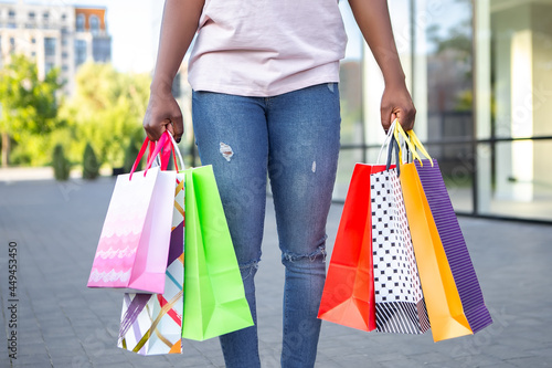 Afro american lady hold hands many bags shopper african woman dressed plain t-shirt carrying enjoying new clothes packs things after shopping buyings sales black friday concept