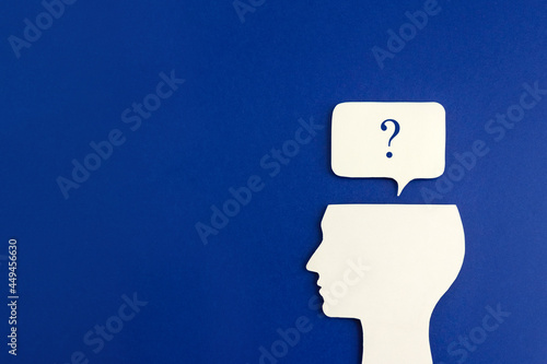 Silhouette of human head and question mark on blue background. The concept of setting problem and its solution. Copy space