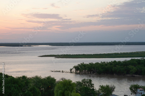 Magical view of the river at sunset. Aerial view of the green jungle, shore, horizon and flowing river with beautiful dusk colors. 