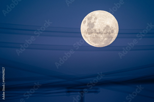 super luna con cielo celeste y encuadre con cables y postes de electricidad