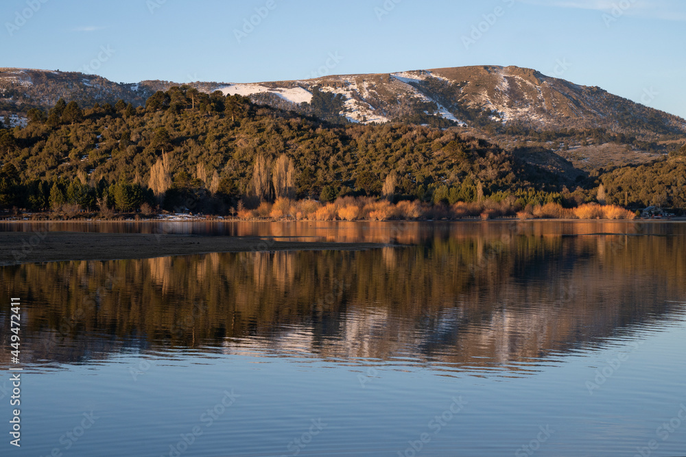 Symmetry in nature. Enchanting view of the Andes mountain range, forest and sky, and the reflection in lake Aluminé water surface at sunset, in Villa Pehuenia, Neuquén, Patagonia Argentina. 