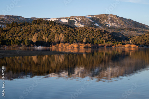 Symmetry in nature. Enchanting view of the Andes mountain range, forest and sky, and the reflection in lake Aluminé water surface at sunset, in Villa Pehuenia, Neuquén, Patagonia Argentina. 
